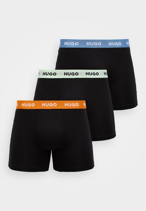 Shorts de boxeur noirs empilés horizontalement, avec des ceintures élastiques colorées en vert menthe, bleu ciel et orange, toutes portant la marque "HUGO".
