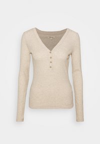 Beżowa bluzka z długim rękawem w serek, z plisą na pięć guzików, o miękkiej fakturze i dopasowanym kroju. Gładki, minimalistyczny wygląd.