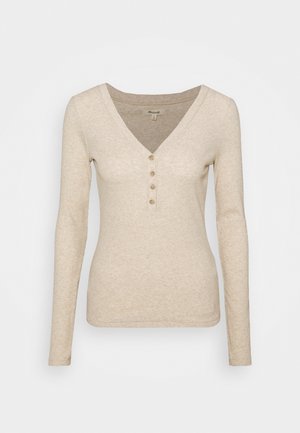 Beżowa bluzka z długim rękawem w serek, z plisą na pięć guzików, o miękkiej fakturze i dopasowanym kroju. Gładki, minimalistyczny wygląd.