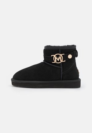 Bottes cheville en daim noir avec bout rond, doublure intérieure en peluche, accent de logo doré et détail de sangle. Semelle en caoutchouc plate pour le confort.