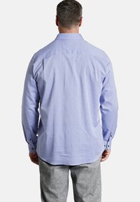 Hellblaues Langarmhemd mit einem dezenten Muster, geradem Saum und Knopfmanschetten, kombiniert mit grauen karierten Hosen.