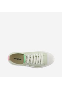 Zapatilla de lona verde con puntera de goma blanca, cordones blancos y acentos en tonos pastel contrastantes en el talón y la lengua. Logotipo de la marca visible en el interior.