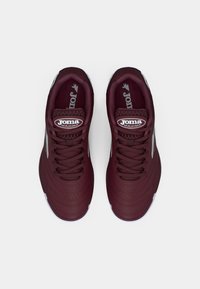 Μπορντό αθλητικά παπούτσια με υφασμάτινο συνθετικό επάνω μέρος, έξι ζεύγη οπών για κορδόνια, λογότυπο Joma και λευκή καουτσούκ σόλα με λεπτομερή σχεδίαση.