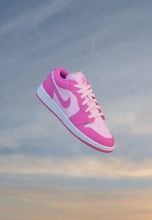 Ροζ και ανοιχτό ροζ αθλητικό παπούτσι Nike Air Jordan με λευκά κορδόνια, αιωρούμενο πάνω σε έναν σύννεφο γαλάζιο ουρανό.