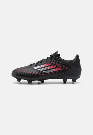 Chaussure de football noire avec un design graphique rouge et blanc, fermeture à lacets, et crampons mixtes coniques et en lame sous la semelle.