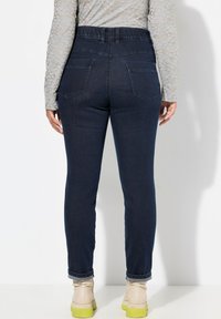 Mörkblå jeans med en avsmalnande passform, med hög midja, uppvikta fållar och bakfickor. Tillverkade av denim med en mjuk yta.