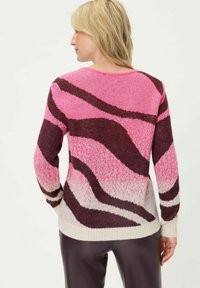 Gestrickter Pullover mit welligem rosa und dunkelbraunem Muster, mit Rundhalsausschnitt sowie gerippten Bündchen und Saum. Hergestellt aus weichem, strukturiertem Garn.