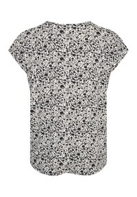 Blouse à motif floral avec un fond blanc, manches courtes, ourlet arrondi et fleurs noires. Réalisée en tissu léger, non doublée.