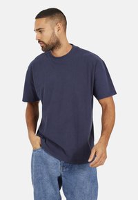 T-shirt en coton bleu marine avec un col ras du cou et des manches courtes. Coupe décontractée avec des détails de couture subtils et une texture douce.