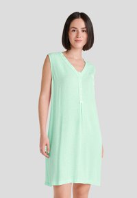 Vestido de dormir verde claro hecho de una tela suave y texturada, con cuello en V, detalles de botones y un bolsillo en el lado izquierdo.