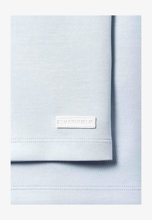 Světlomodrá látka složená, s malou bílou obdélníkovou nášivkou s raženým textem "ELIASRUMELIS" poblíž spodního okraje.