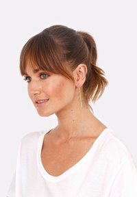 Goldene Tropf ohrringe mit einem schlanken, geraden Design und kleinen runden Akzenten. Das Model trägt ein weißes T-Shirt, die Haare im Pferdeschwanz frisiert.