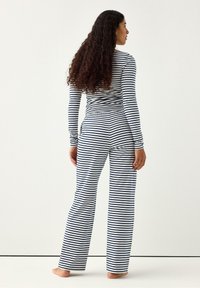 Randigt loungset i marinblått och vitt. Långärmad topp med matchande byxor med avslappnad passform och elastisk midja. Bomullsmaterial.