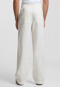 Vita linnebyxor med breda ben, elastisk midja och två bakfickor. Mjuk textur och lättviktig tyg.