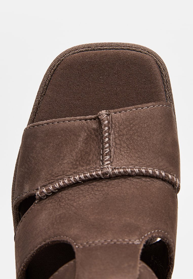 Sandalia de cuero marrón con punta cuadrada, que presenta diseños recortados y costuras en contraste a lo largo de los bordes para un detalle textural.