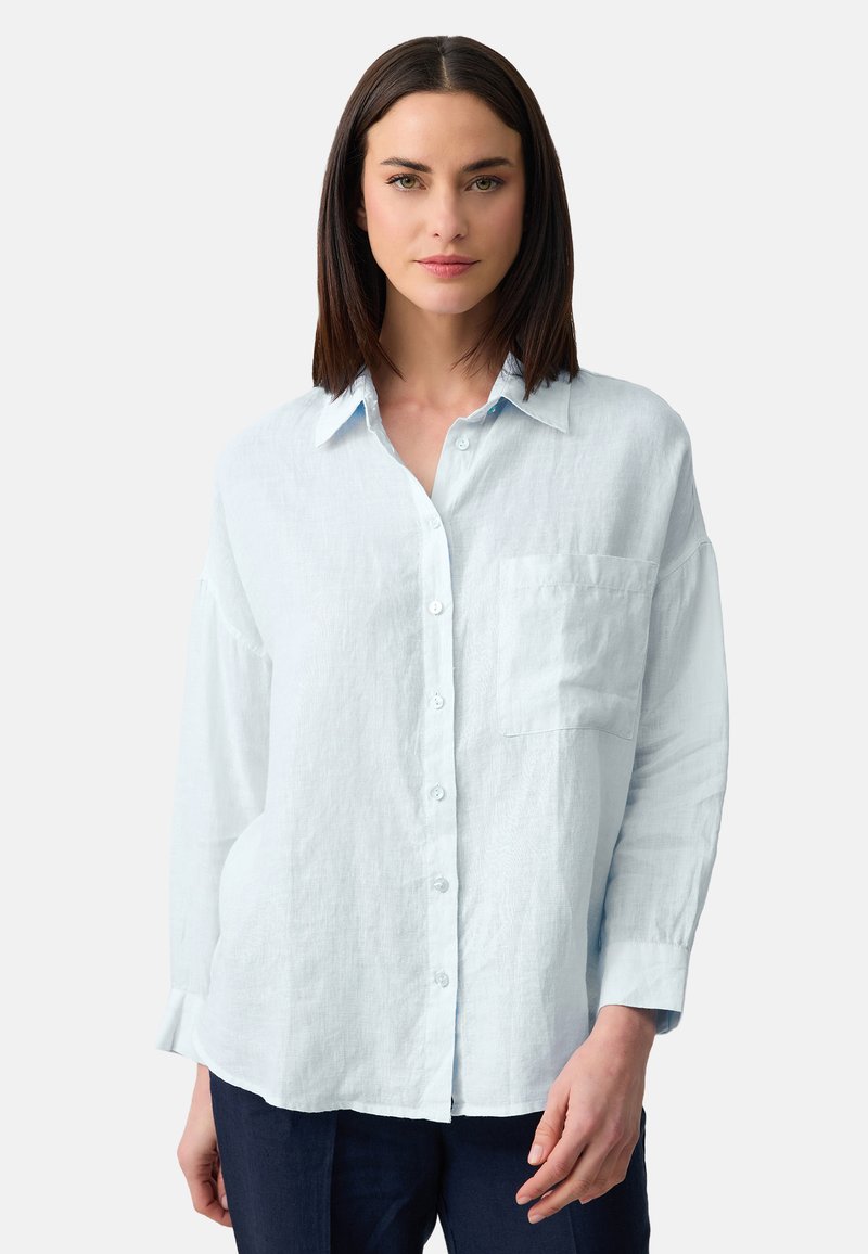 Lichtblauwe lange mouwen shirt gemaakt van een zachte, gestructureerde stof. Beschikt over een knoopsluiting aan de voorkant en een enkele borstzak.