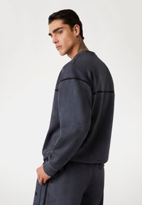 Navyblauwe sweatshirt van zacht stof, met een ronde halslijn en een horizontale streep over de rug. Eenvoudig, ontspannen ontwerp.