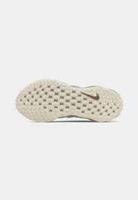 Skosål med lys beige gummi, der har et gittermønster og et lille brunt Nike-logo. Den teksturerede overflade hjælper med traction og greb.