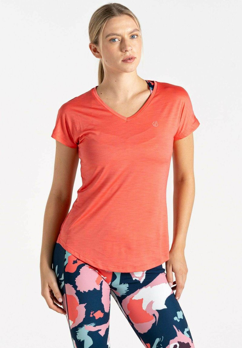 Camiseta de cuello en V en color coral, hecha de un tejido ligero, con mangas cortas, combinada con leggins estampados en tonos marino, rosa y blanco.