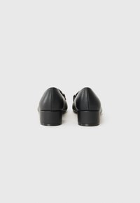 Black leather shoes with a rounded toe, a low block heel, and a smooth texture. Features minimalistic design with no prominent accents.