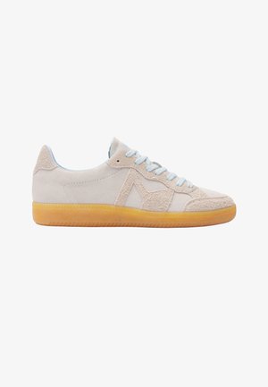 Baskets blanches en suède avec des détails texturés sur les côtés, des lacets bleu clair et une semelle en caoutchouc ambre translucide, vues de profil sur un fond blanc.