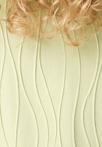 Gestructureerde lichtgroene stof met golvende gestikte patronen van verschillende hoogtes, die de krullende haren bovenaan de afbeelding aanvullen.