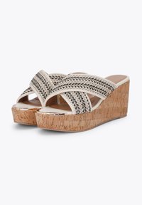 Sandales à talon en liège avec des brides tressées croisées en noir et beige, dotées d'un intérieur lisse et d'un talon épais pour plus de hauteur.