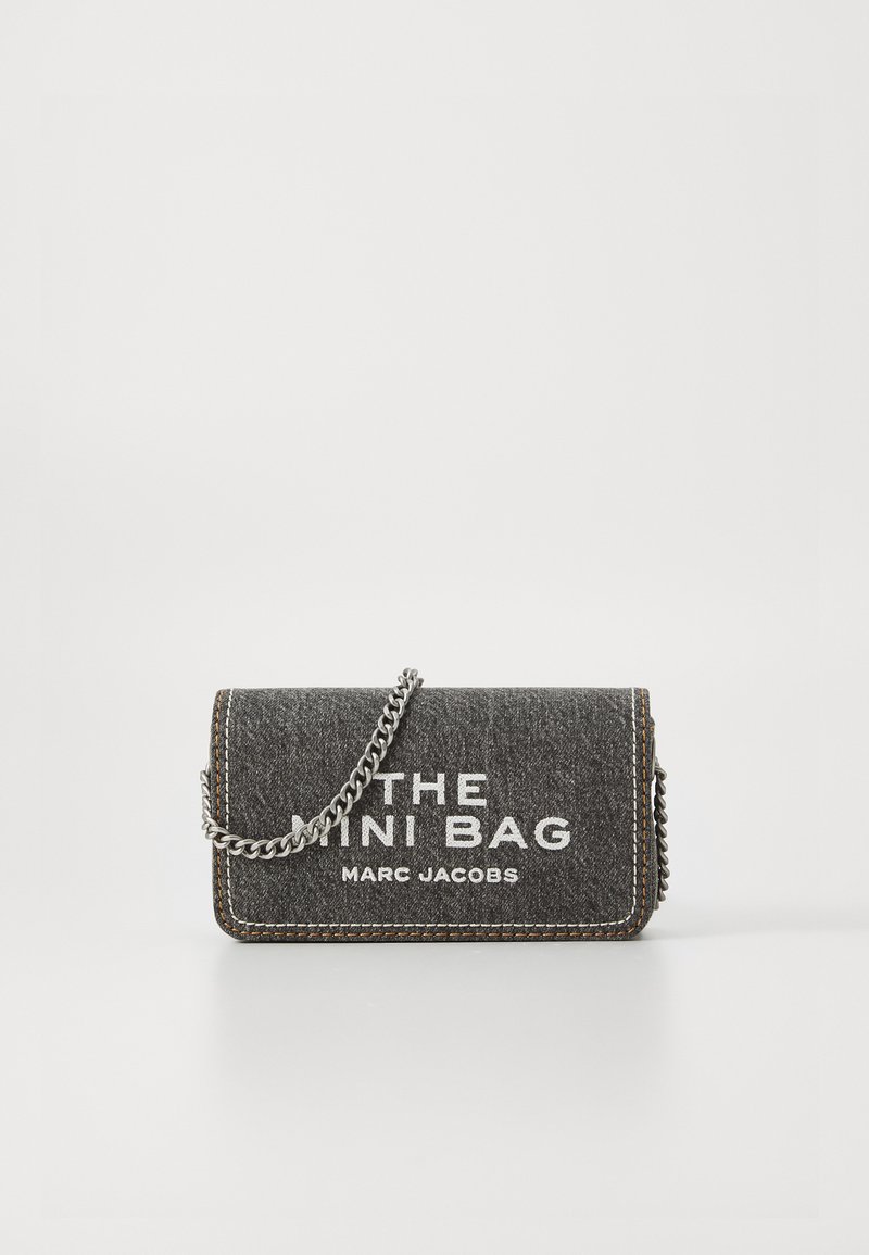 Mini bolsa de tecido cinza escuro com o texto branco "A MINI BOLSA MARC JACOBS" e uma alça de corrente prateada em um fundo branco.