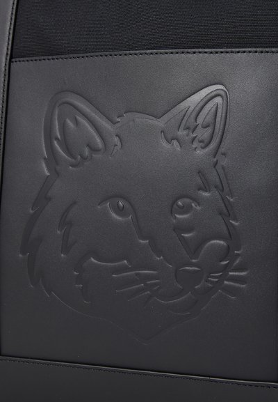 Producto de cuero negro con un diseño de lobo elevado y en relieve, con rasgos faciales definidos y textura suave.