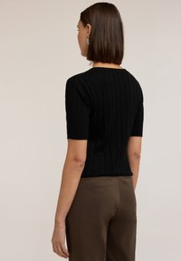 Zwarte geribbelde trui met korte mouwen en een slim-fit ontwerp. Heeft een ronde halslijn en een gestructureerde stof. Gekocht met bruine op maat gemaakte broeken.