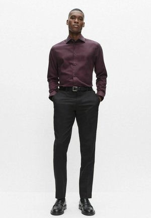 Långärmad vinröd skjorta med knappar, kombinerad med svarta byxor och läderskor. Mjukt tyg med klassisk krage och åtsittande design.