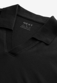 Polo noir coupe régulière avec une étiquette de taille moyenne et un col, fabriqué au Bangladesh.