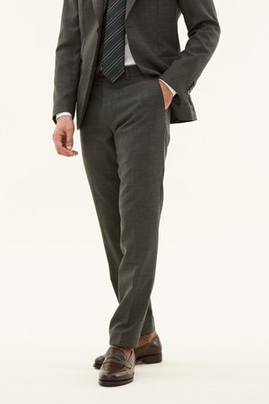 Pantaloni grigi su misura con un tessuto strutturato, fit dritto, tasche laterali, abbinati a mocassini in pelle marrone scuro.