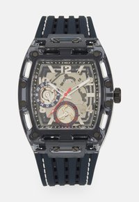 Transparente rechteckige Uhr mit einem dunkelblauen Gummiband. Verfügt über ein graues Zifferblatt, schwarze Akzente und rote Details auf den Unterzifferblättern.