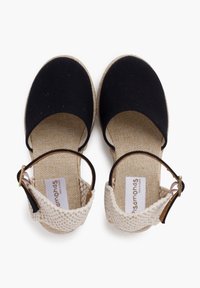 Zwarte canvas espadrilles met een geweven beige enkelband, voorzien van een lichtbruine textuurzool en een gesp-sluiting.