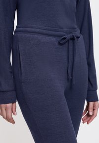 Marinblått lounge-set i mjukt, texturerat material, med dragsko i midjan och sidofickor för ökad funktionalitet.