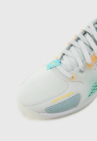 Hellblaues Sportschuh mit Mesh-Obermaterial und gelben Akzenten, strukturierten Seitenpaneelen und türkisfarbenem Markenlabel. Abgerundete Zehenform.