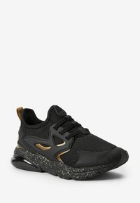 Czarne sportowe sneakersy z oddychającą siateczką, teksturowanymi czarnymi akcentami, złotymi detalami oraz plamistą czarną gumową podeszwą.