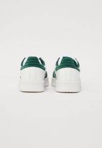 Hvite sneakers med grønne semskede detaljer, teksturert bakside og polstret krage. Gummisåle med et rent design og minimalt detaljer.