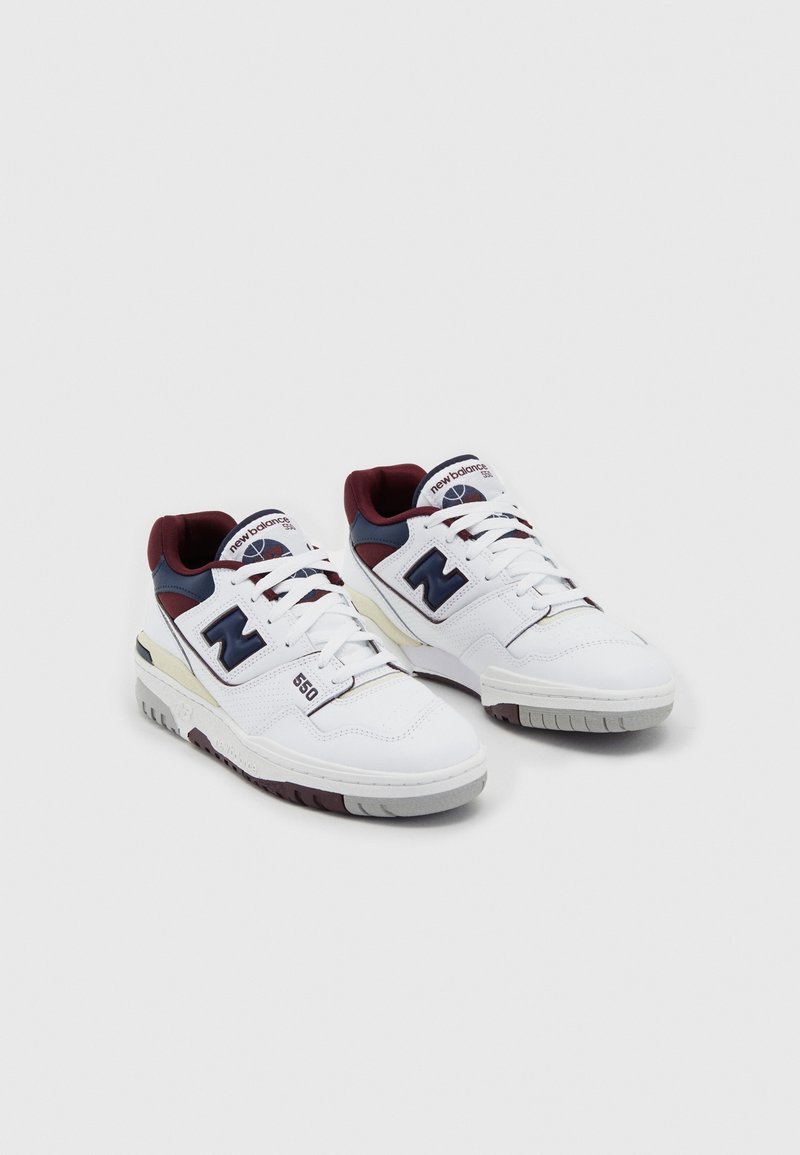 Paire de baskets blanches New Balance 550 avec des accents bleu marine et bordeaux, lacets blancs et marquage de la marque sur les côtés et les languettes.