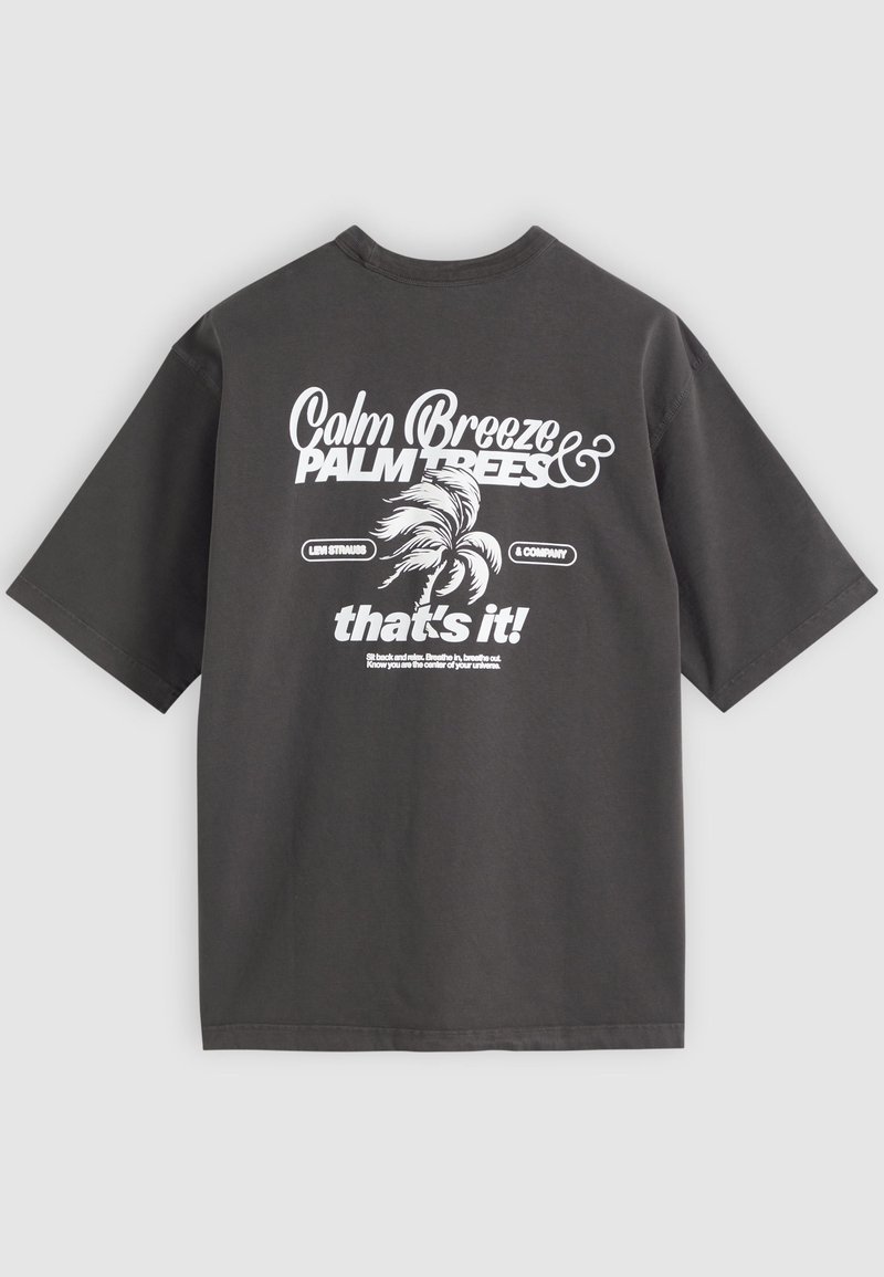 Dark gray t-shirt with white text "Calm Breeze & Palm Trees," a palm tree graphic, and additional small printed text on the back.