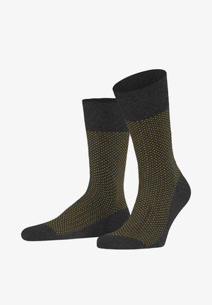 Graue Socken mit einem gerippten oberen Rand und einem strukturierten Design, das gelbe und blaue Punkte zeigt, die in einem Muster angeordnet sind und zur Zehe hin verjüngen.