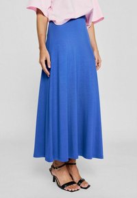 Maxi-Rock in leuchtendem Blau, aus einem weichen, leichten Stoff gefertigt. Verfügt über ein fließendes Design mit einer glatten Oberfläche. Kombiniert mit schwarzen Riemchensandalen.