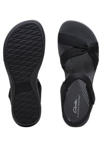 Schwarze Flip-Flop-Sandalen mit strukturierten Gummisohlen, weichen Stoffriemen und einem gepolsterten Fußbett in schlichtem Design mit Logo.