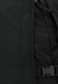 Schwarzer Rucksack aus einem strukturierten Material, mit einem Reißverschluss und verstellbarem Riemen. Enthält eine Kunststoffschnalle und verstärkte Nähte.