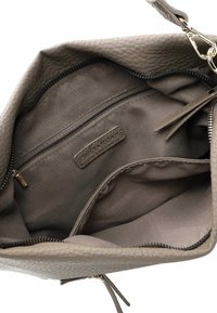 Interno di una borsa a tracolla in pelle grigia texturizzata con una fodera di tessuto. Presenta una tasca con zip e un'etichetta del marchio cucita nella fodera.