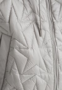 Graue gesteppte Jacke mit Sternenmuster, ausgestattet mit metallic-farbenen Nähten, einem Reißverschluss vorne und einer Kapuze mit Kordelzug. Glatte Textur mit glänzender Oberfläche.