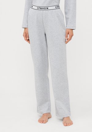 Grey sweatpants with a relaxed fit, made of cotton, featuring a black and white elastic waistband with "CPNHGN" branding. Bare feet visible.