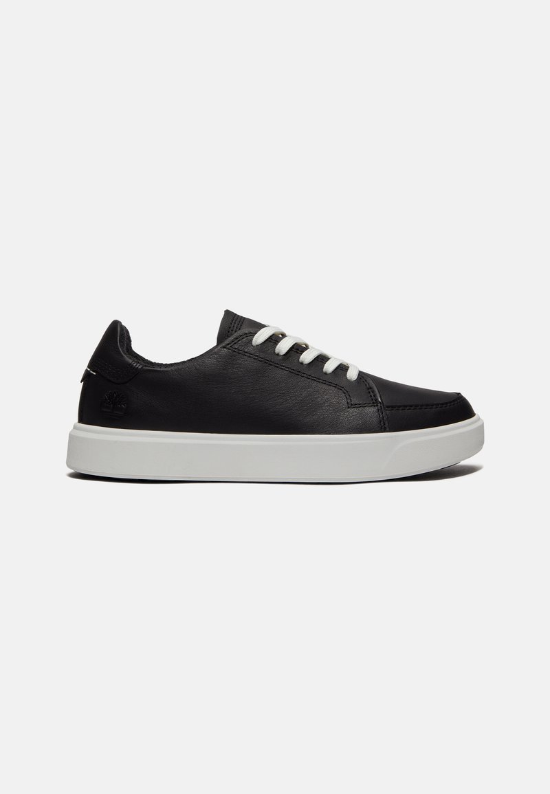Zapatillas de cuero negro con cordones blancos, suela de goma blanca y un logo en el talón. Textura suave con un diseño clásico de corte bajo.