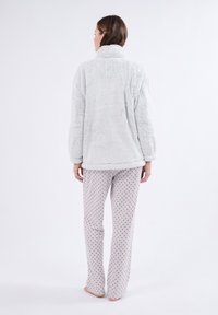 Jasnoszara puszysta kurtka z wysokim kołnierzem, zestawiona z szarymi spodniami od piżamy z małymi czerwonymi kropkami; zarówno casualowa, jak i wygodna.